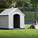 Dog sitting on lawn by a dog house