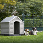 Two dogs sitting on the lawn by a dog house