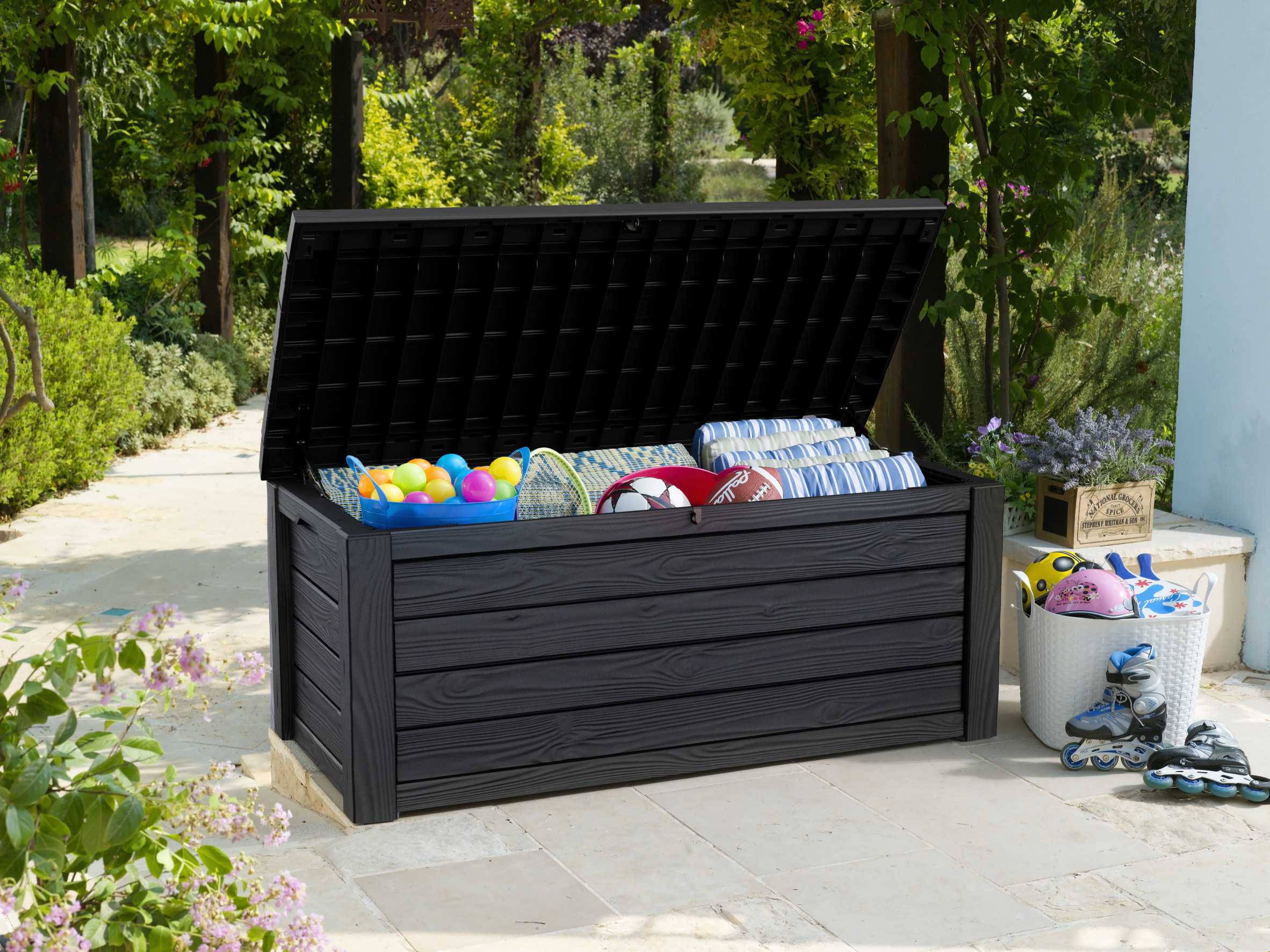 Outdoor cushion box with lid open filled with cushions and sports gear