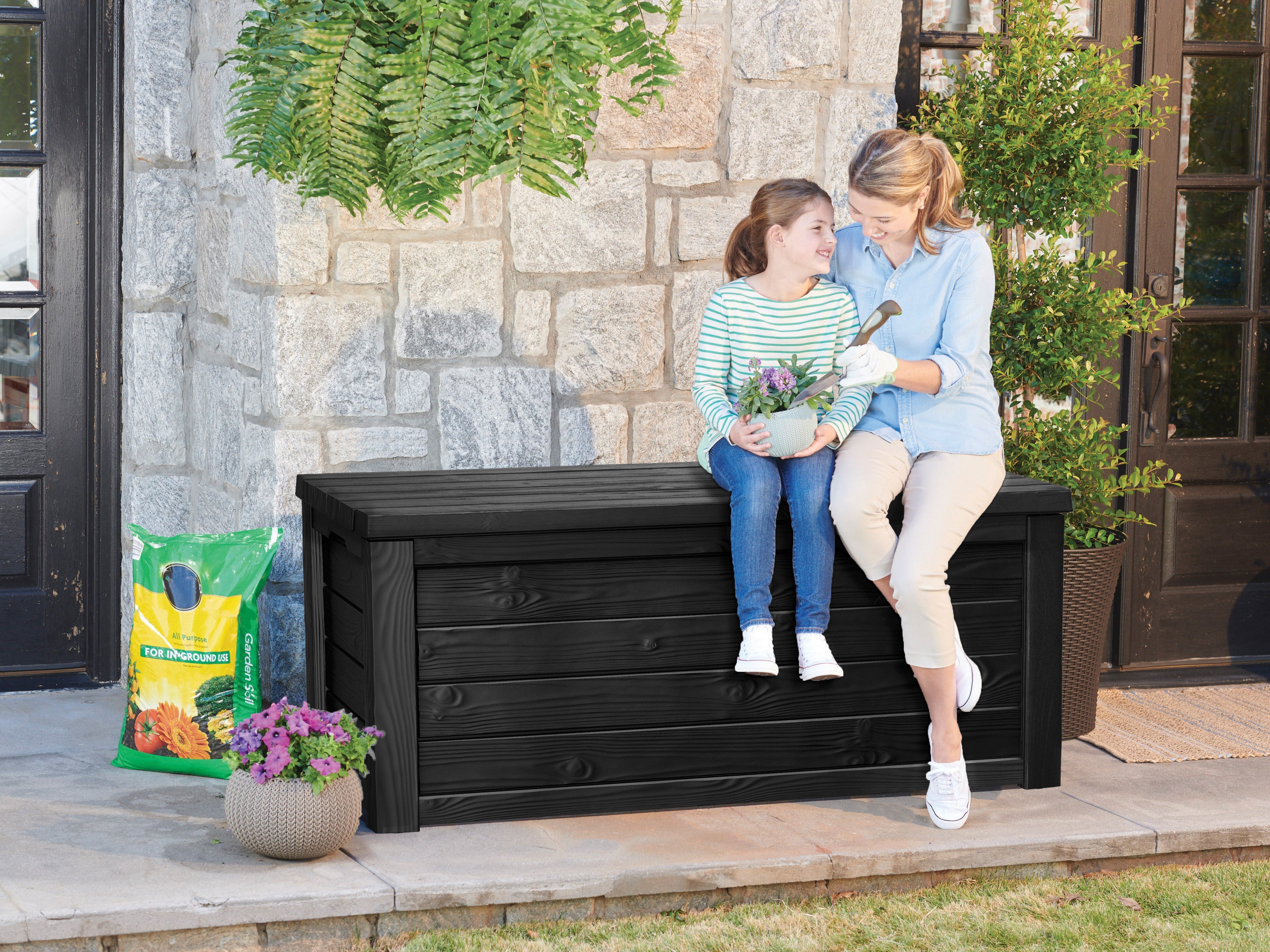 Mother and daughter sitting on the lid of the Keter Eastwood cushion box