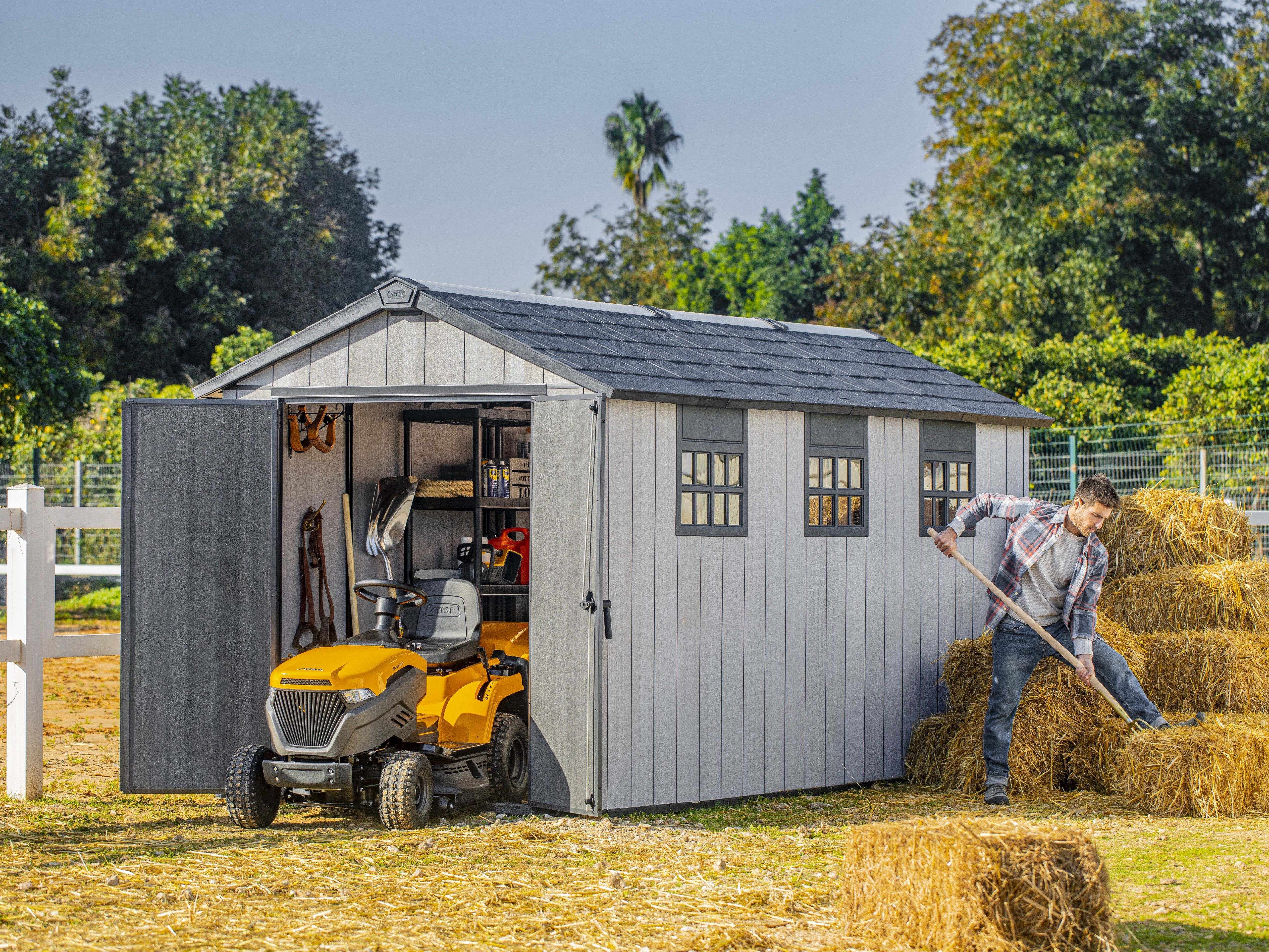 Keter Oakland 7515 shed on sunny day with haybales and ride on mower