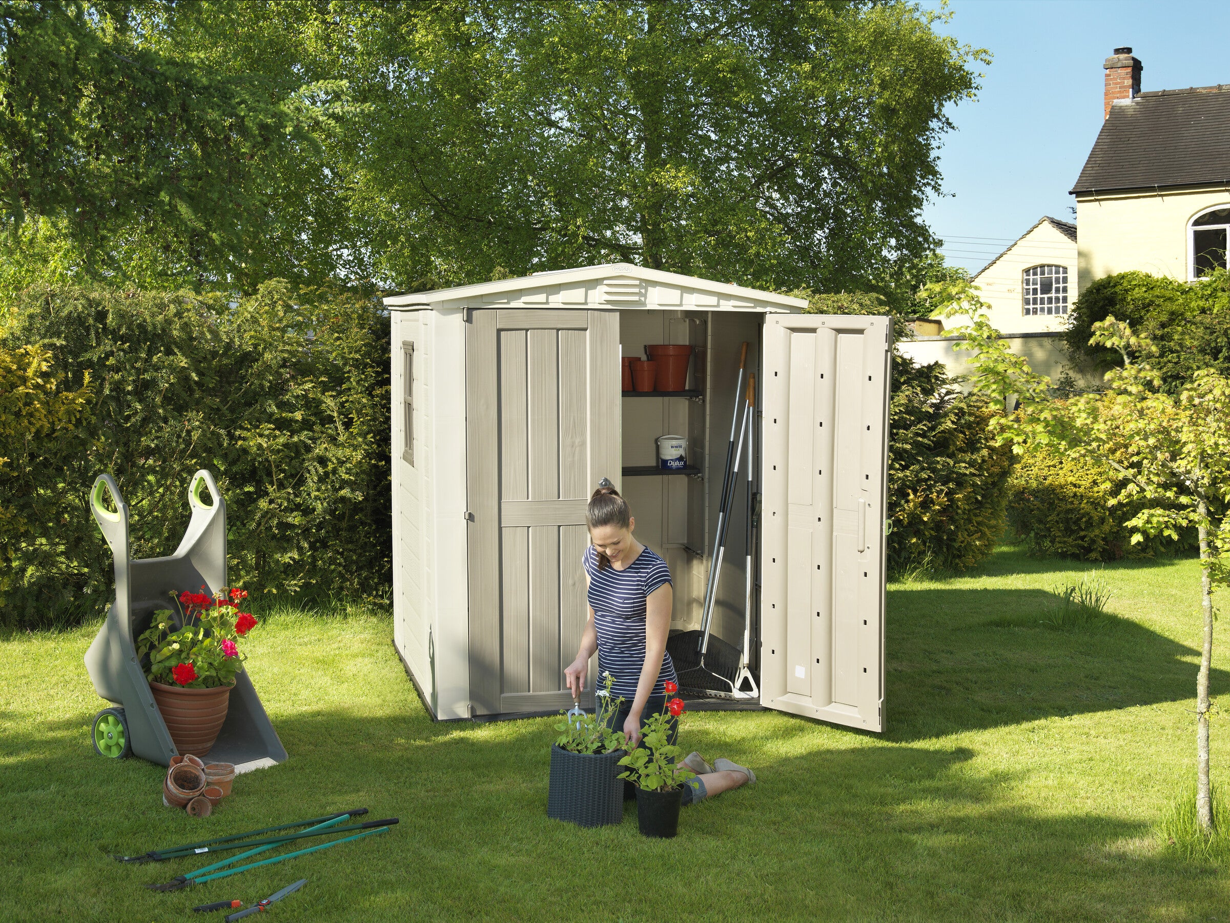 A woman potting plants in front of the factor 6x6 Shed